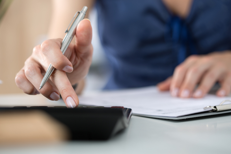 Close up of female accountant or banker making calculations. Savings, finances and economy concept
